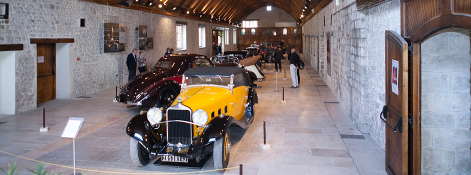 Exposition de voitures anciennes dans la salle des Grands Moulins, avec une Delage D8 jaune et noire.